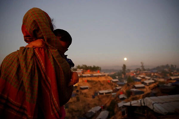 A Rohingya refugee looks at the full moon with a child in tow at Balukhali refugee camp