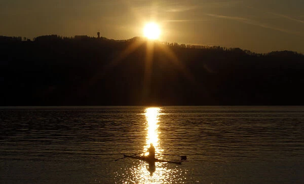 A rower is seen during sunset on Lake Zurich on a mild and sunny spring day near Kuesnacht