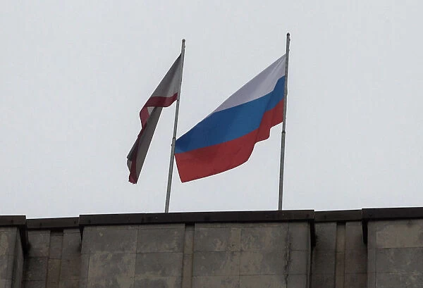 A Russian flag is raised next to a Crimean flag on top of the Crimean parliament building