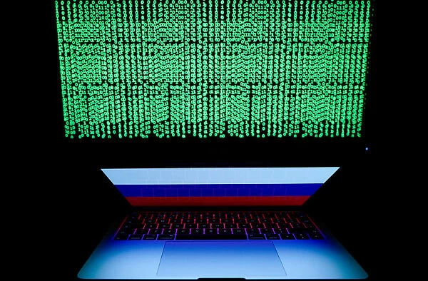 Russian flag is seen on the laptop screen in front of a computer screen on which cyber