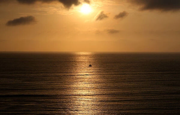 A sailboat sails during sunset in the Pacific Ocean in Lima
