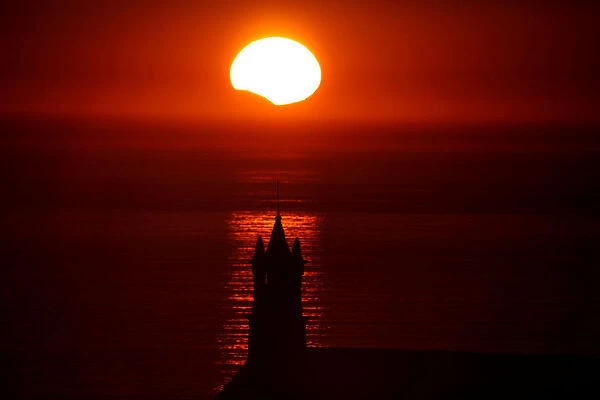 The Saint-They Chapel is seen in silhouette at sunset during a partial solar eclipse as