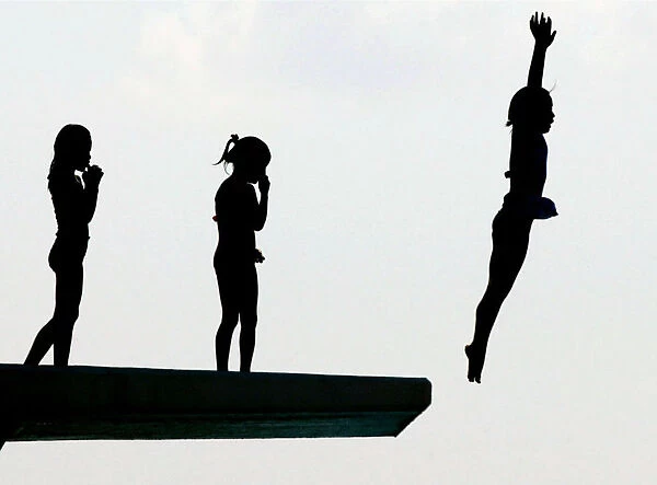 Schoolgirls dive from a five-metre platform at a swimming pool in Oiso