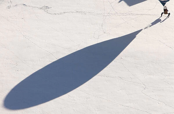 The shadow of a balloon is cast on the snow covered ground as it just landed during