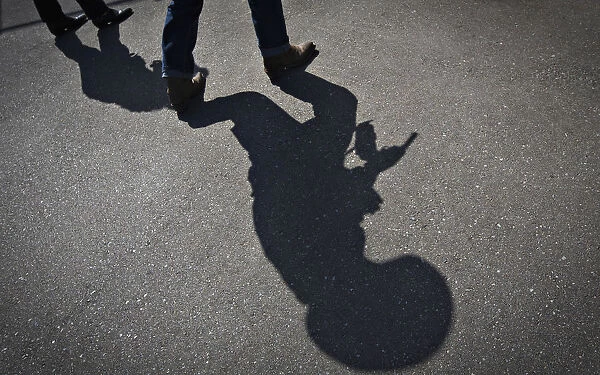 The shadow of a gunfighter is cast on the asphalt as competitors practice prior to