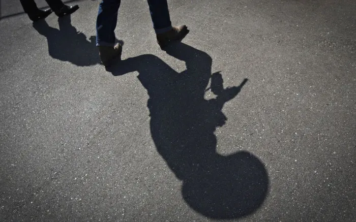 Framed Print : The shadow of a gunfighter is cast on the asphalt as competitors practice prior to