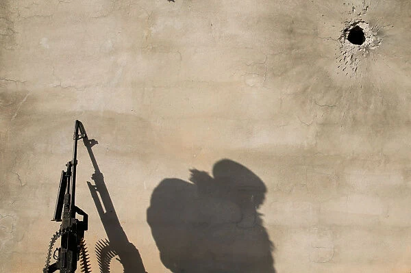 The shadow of a member of the Iraqi Army is cast on a wall during clashes with Islamic