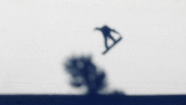The shadow of a snowboarder is cast on the half pipe as he takes part in a half pipe