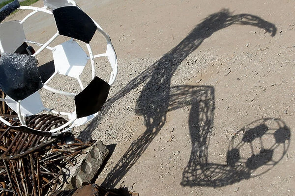 A shadow of the statue depicting soccer player and made from the scrap metal is seen