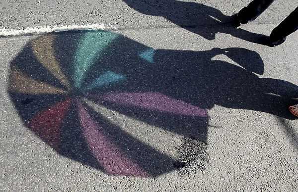 The shadow of an umbrella is cast on the ground during the annual gay pride parade