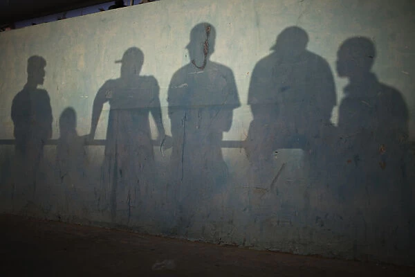 Shadows are cast on the wall of a stadium as people watch a traditional wrestling