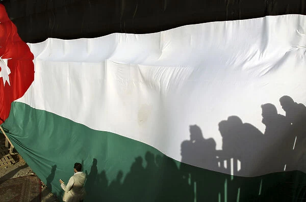Shadows of people were cast on a large Jordanian national flag during a celebration to