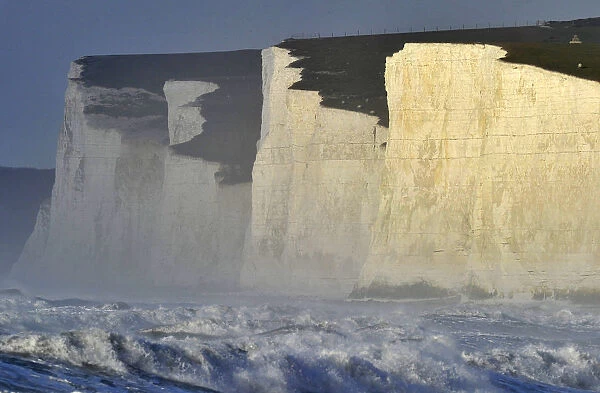Sheep graze along the top of the Seven Sisters cliffs as heavy seas are seen in the
