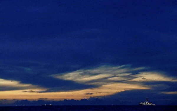 A ship sails toward the Colombo Harbor as the sun sets in Colombo