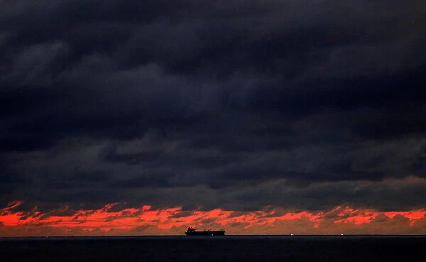 A ship sails towards Colombo main harbour as the rainy clouds gathered above the sunset