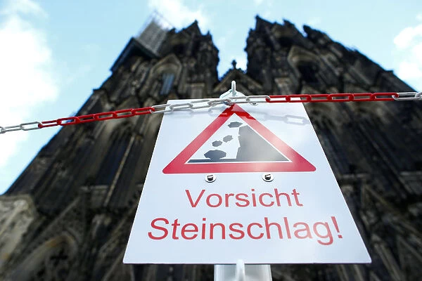 A sign reads attention stones in front of the Cologne Cathedral