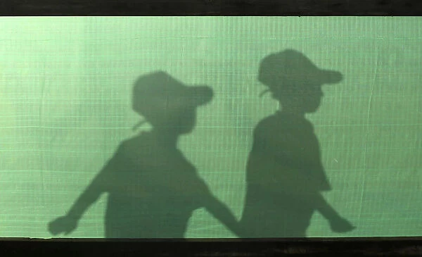 The silhouettes of Palestinian boys are seen as they arrive for a summer camp organised