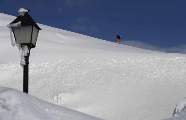 A skier walks in the snow at the mountain pass of Pajares