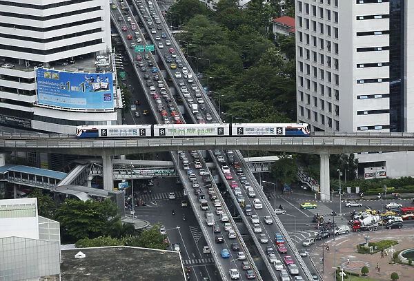 A skytrain passes over vehicles on the road during rush hour in Bangkok