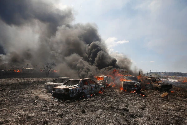 Smoke billows from burning cars during a fire at a plot where police kept seized vehicles