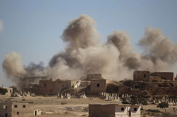 Smoke rises behind the ancient castle of the rebel-controlled town of Maaret al-Numan