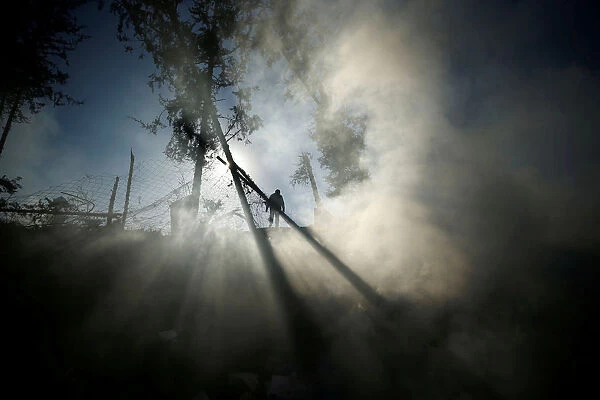 Smoke is seen as a Palestinian man inspects a militant target that was hit in an Israeli