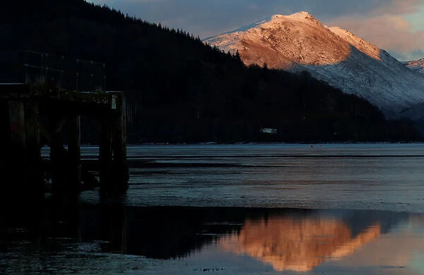 Snow capped mountains are reflected in Loch Fyne, as seen from Inveraray, Scotland