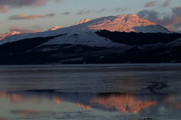 Snow capped mountains are reflected in Loch Fyne, as seen from Inveraray, Scotland