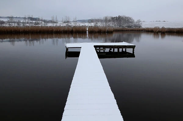 Snow covered pier is seen on a lake near the village of Etyek