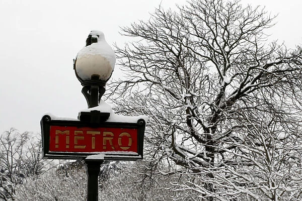 Snow covers a Metro sign and tree branches as winter conditions with snow