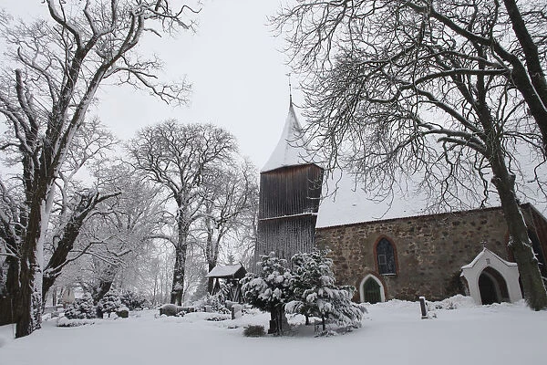 Snow covers the trees in the cemetery of a church in the village of Dersekow in northern