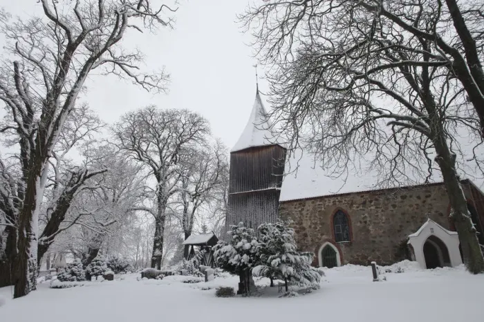 Framed Print : Snow covers the trees in the cemetery of a church in the village of Dersekow in northern