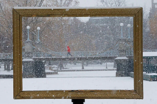 Snow falls through a picture frame in the Boston Public Garden during a winter storm in