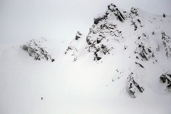 A snowboarder descends from a rough mountain slope towards Balea glaciar lake at Balea