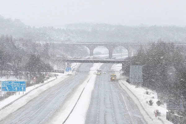 Snowploughs work on the M80 motorway after it was closed to clear vehicles stranded by