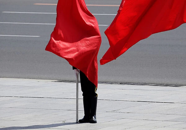 A soldier from the honour guards is covered by a red flag during a welcome ceremony for
