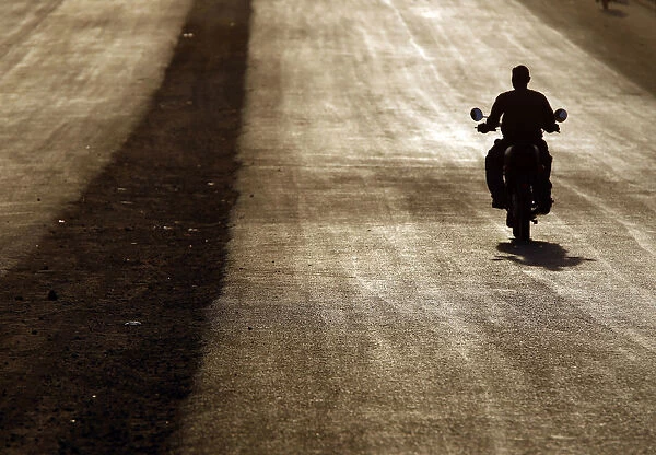 A southern Sudanese man rides a motorcycle during sunset in Juba
