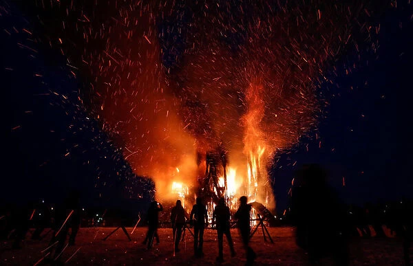 Spectators look at the burning installation during a performance devoted to Maslenitsa in