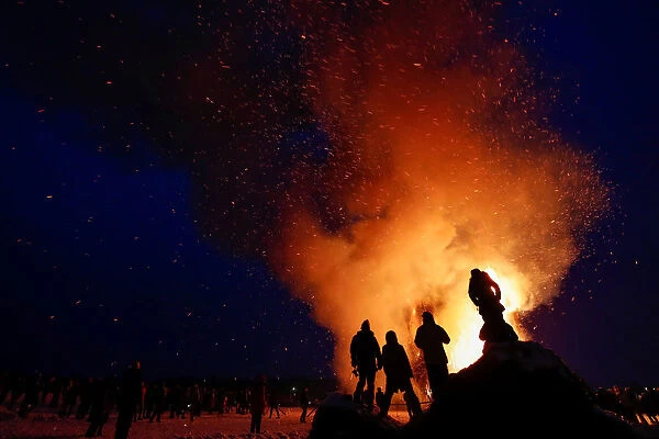 Spectators look at the burning installation during a performance devoted to Maslenitsa in