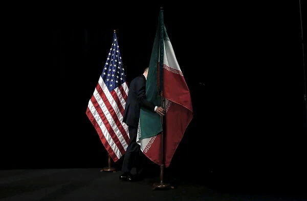 A staff member removes the Iranian flag from the stage after a group picture with foreign