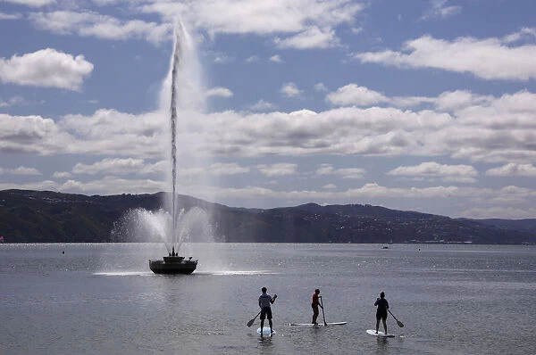 Stand up paddleboard riders float past the Carter Fountain located in Oriental Bay