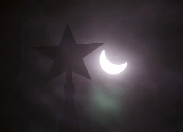 A star on the top of the tower of the Kremlin is seen during a partial solar eclipse in