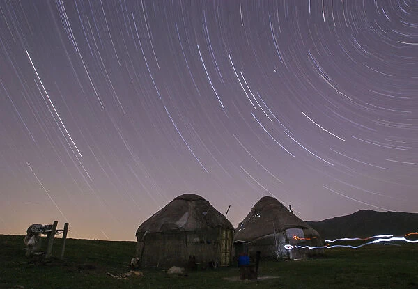 Star trails form over yurts in a long exposure picture on the mountainous Assy plateau