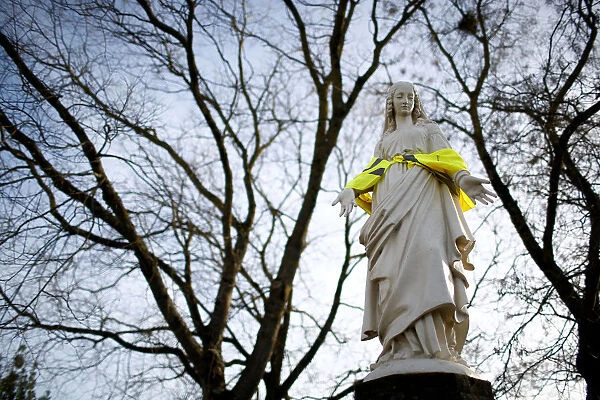 A statue of the Virgin Mary wears a yellow vest in a street in Nantes