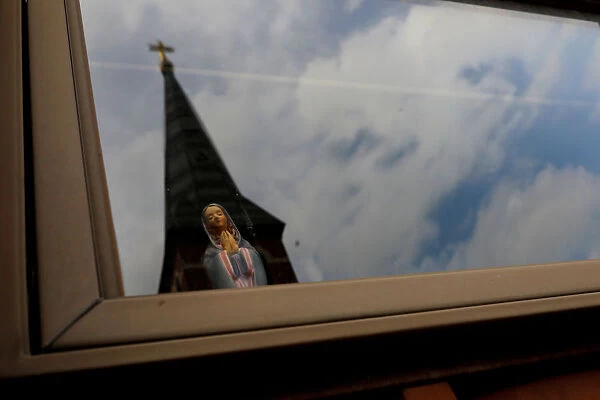 Statuette of Virgin Mary is seen inside of a house in front of Charles Borromeo Parish