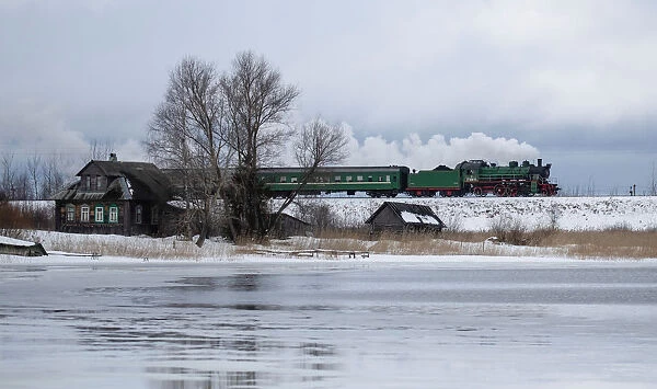 A steam train passes by along a dam outside Ostashkov