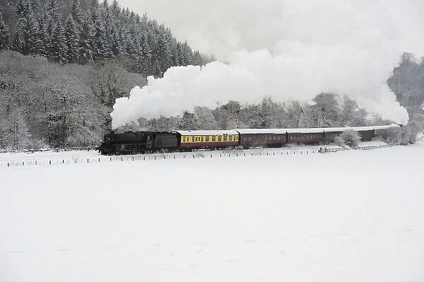 A steam train is seen running through a snow covered valley between Pickering