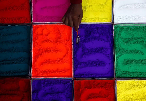 A street vendor spreads vermilion powder used for worship during the Tihar festival