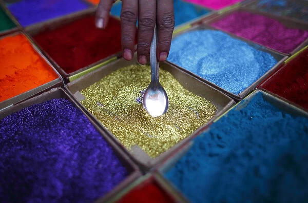 A street vendor spreads vermilion powder used for worship during the Tihar festival in