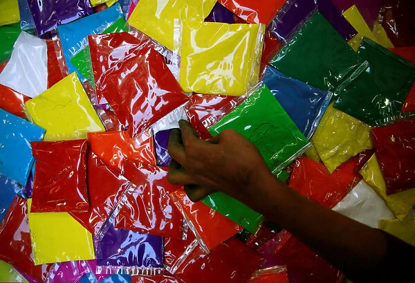 A street vendor takes a packets of vermilion powder kept on sale ahead of Tihar festival